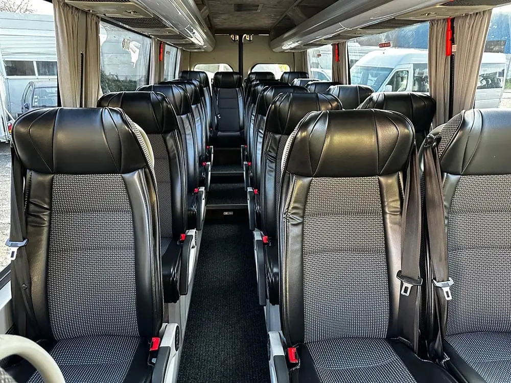 Interior of a 19-seater Mercedes Sprinter coach showing black leather seats with a sleek design, available for comfortable group transport in Paris